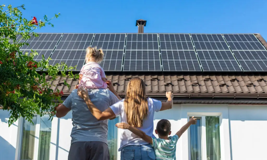 Famille devant une maison individuelle équipée de panneaux solaires photovoltaïques en autoconsommation